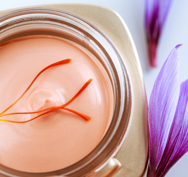 Un pot de crème hydratante entouré de fleurs de safran, qui permet de bénéficier de tous les bienfaits du safran en cosmétiques