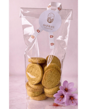 Vue sur un sachet de biscuits sablés au safran à côté de trois fleurs de safran et quelques stigmates rouges