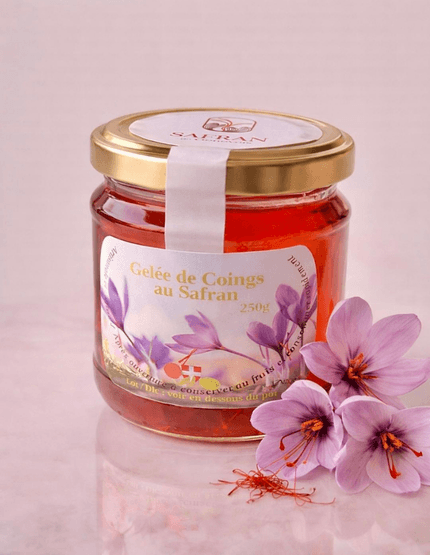 Vue sur un pot de gelée de coings au safran à côté de trois fleurs de safran et quelques stigmates rouges