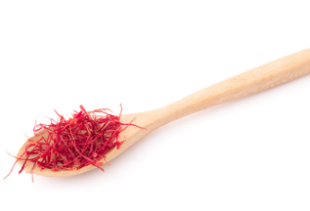 Cuillère en bois remplie de stigmates de safran rouges vifs.